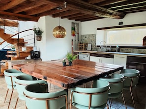 A rustic kitchen with a wooden table and green chairs, a staircase, and a tiled backsplash. - Domaine LVD Country House – Ideal for Events, Private Pool, Terrace & Wi-Fi (La Bloutière)
