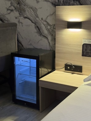 A minibar with a digital display, a wooden nightstand, and a wall-mounted control panel. - VanParkHotel (Shymkent)