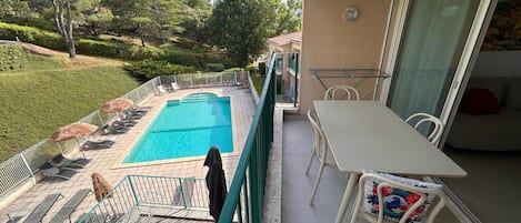 A balcony with a pool, outdoor furniture, and a table.