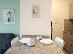 Ein Essbereich mit einem Tisch für zwei Personen, einem gerahmten Zitat an der Wand und einer Küche im Hintergrund.