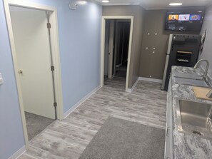 A modern kitchen with a built-in oven, a stainless steel sink, and a flat-screen TV mounted above the counter. - Toluca Laundromat Hotel, Entire Rental Unit. 3 Bedrooms,4 beds. 1 Bath (Toluca)