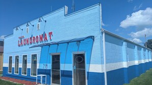 Un edificio azul con el letrero 'TOLUGA LAUNDROMAT' y el número '218' en la fachada.