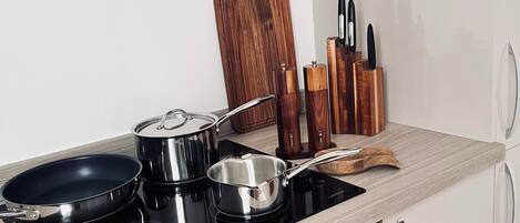 A modern kitchen with a stove, pots, a frying pan, and a digital clock.