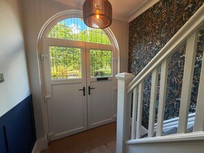 A hallway with a white door, a staircase with white railings, and a floral wallpaper. - 3 Bedroom Apartment 2 up to 5 People Free Parking (Blackpool)