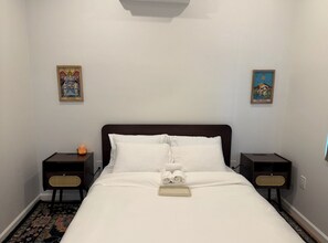 Une chambre d’hôtel avec un grand lit, deux tables de chevet et deux tableaux accrochés au mur.