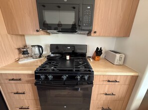 Une cuisine équipée d’une cuisinière, d’un four à micro-ondes, d’un grille-pain et d’une machine à café.