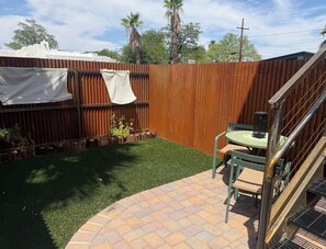 Un patio con mesa y sillas, una valla de madera y un pequeño jardín.