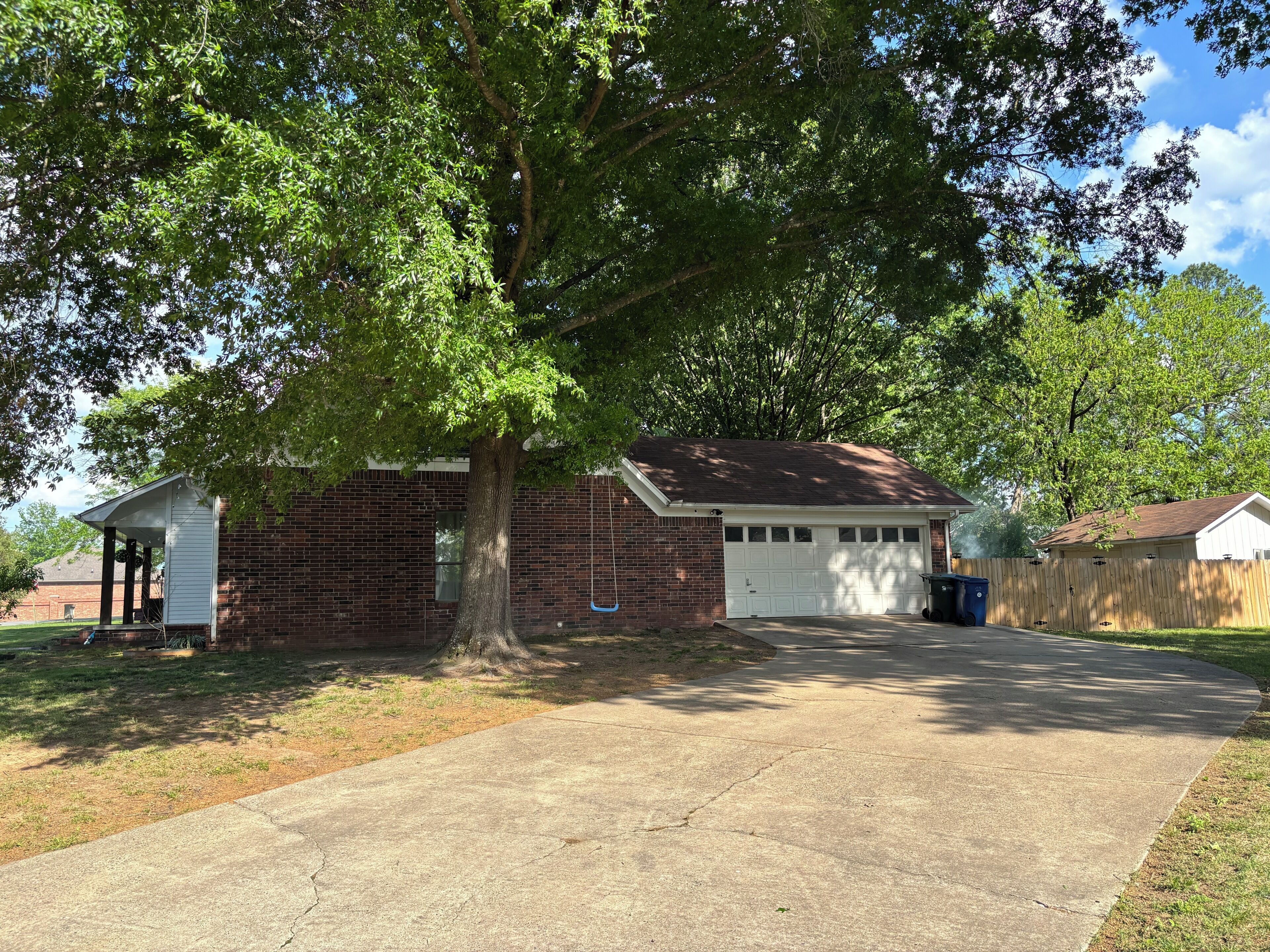 A residential house with a garage, a tree in front, and a clear sky.