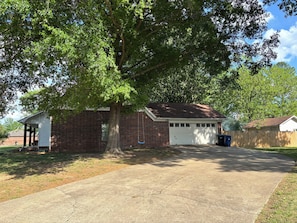 A residential house with a garage, a tree in front, and a clear sky.