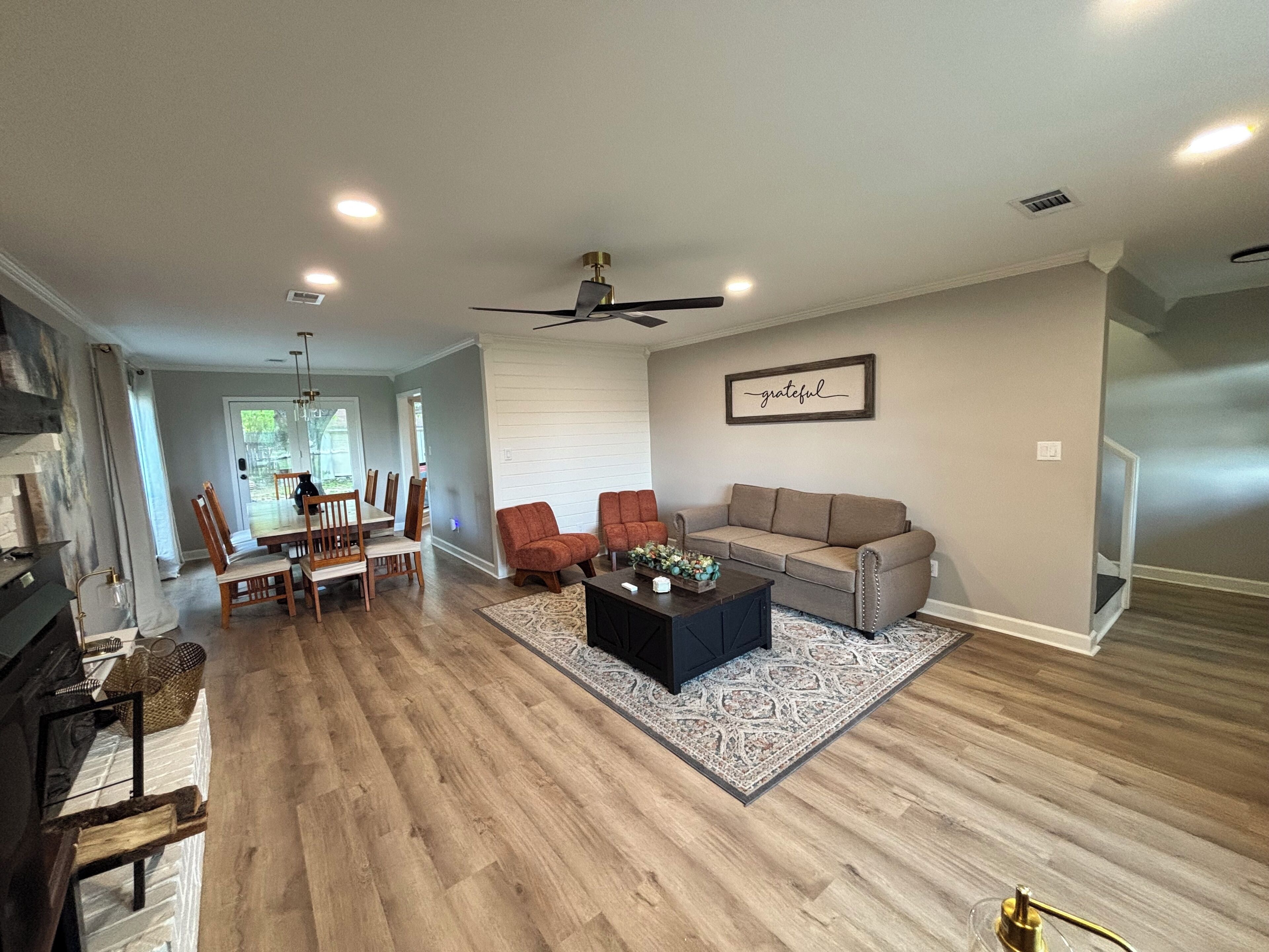A spacious living room with a fireplace, a dining area, and a ceiling fan.