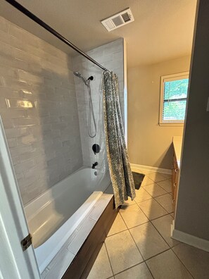 Een moderne badkamer met een douchecabine van glas, witte metrotegels en een raam met zonwering.