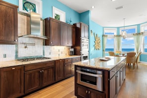A kitchen with dark wood cabinets, a stainless steel range, and a large island with a built-in oven. - Treasure Island On the Sand Pool Hot Tub Slps 12 (Treasure Island)