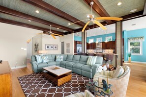 A spacious living room with a sectional sofa, a coffee table, and a dining area with wicker chairs. - Treasure Island On the Sand Pool Hot Tub Slps 12 (Treasure Island)