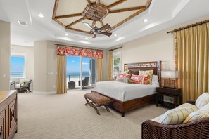 A spacious bedroom with a large bed, a ceiling fan, and a view of the ocean through a sliding door. - Treasure Island On the Sand Pool Hot Tub Slps 12 (Treasure Island)