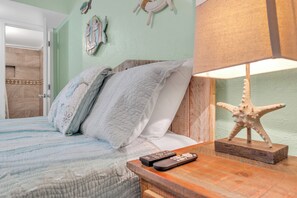 A bed with a wooden headboard, a starfish decoration, and a remote control on a wooden nightstand. - Cozy 1-bedroom studio in charming Gulf Shores with AC (gulf shores)