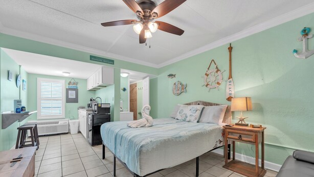 Ein Schlafzimmer mit Bett, Nachttisch, Schreibtisch und Deckenventilator.