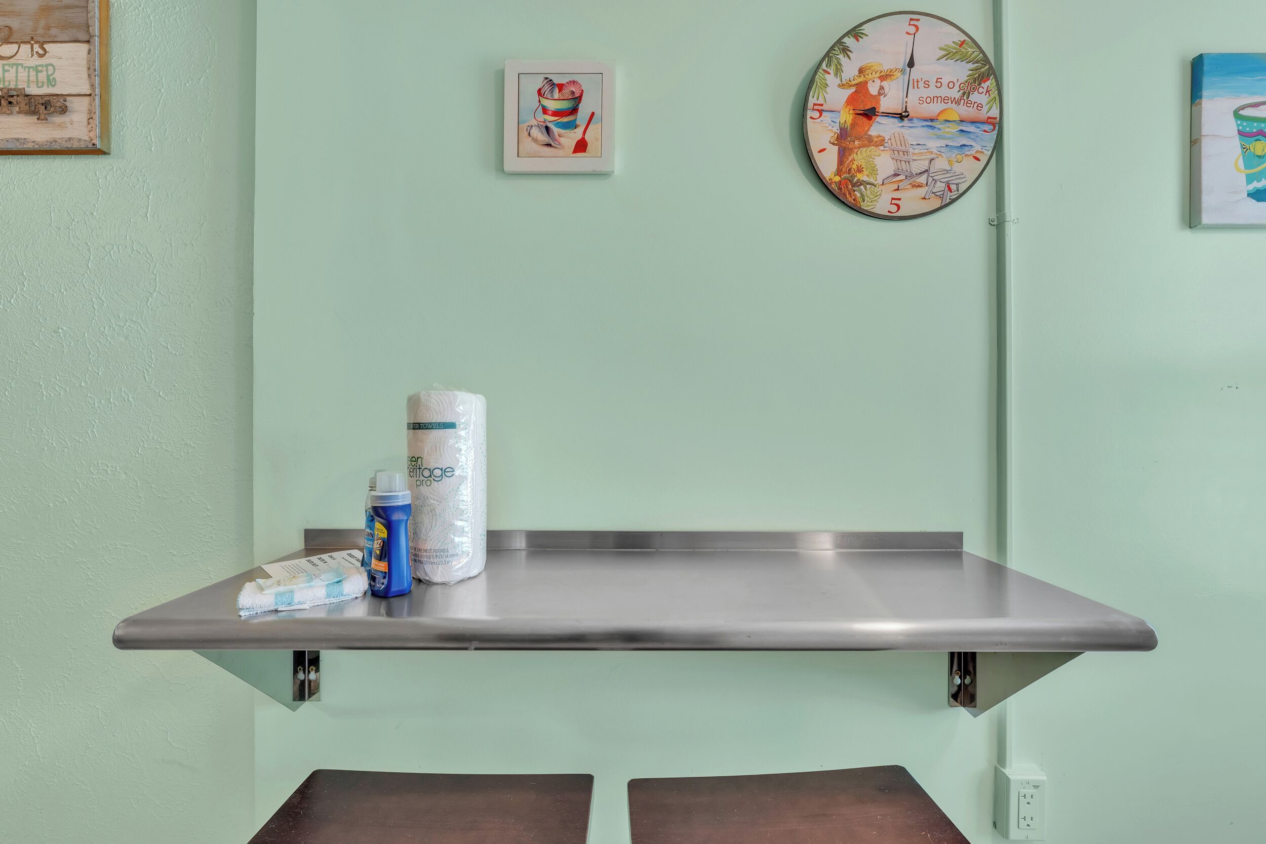 A bathroom with a towel rack, a wall clock, and a shelf with toiletries.