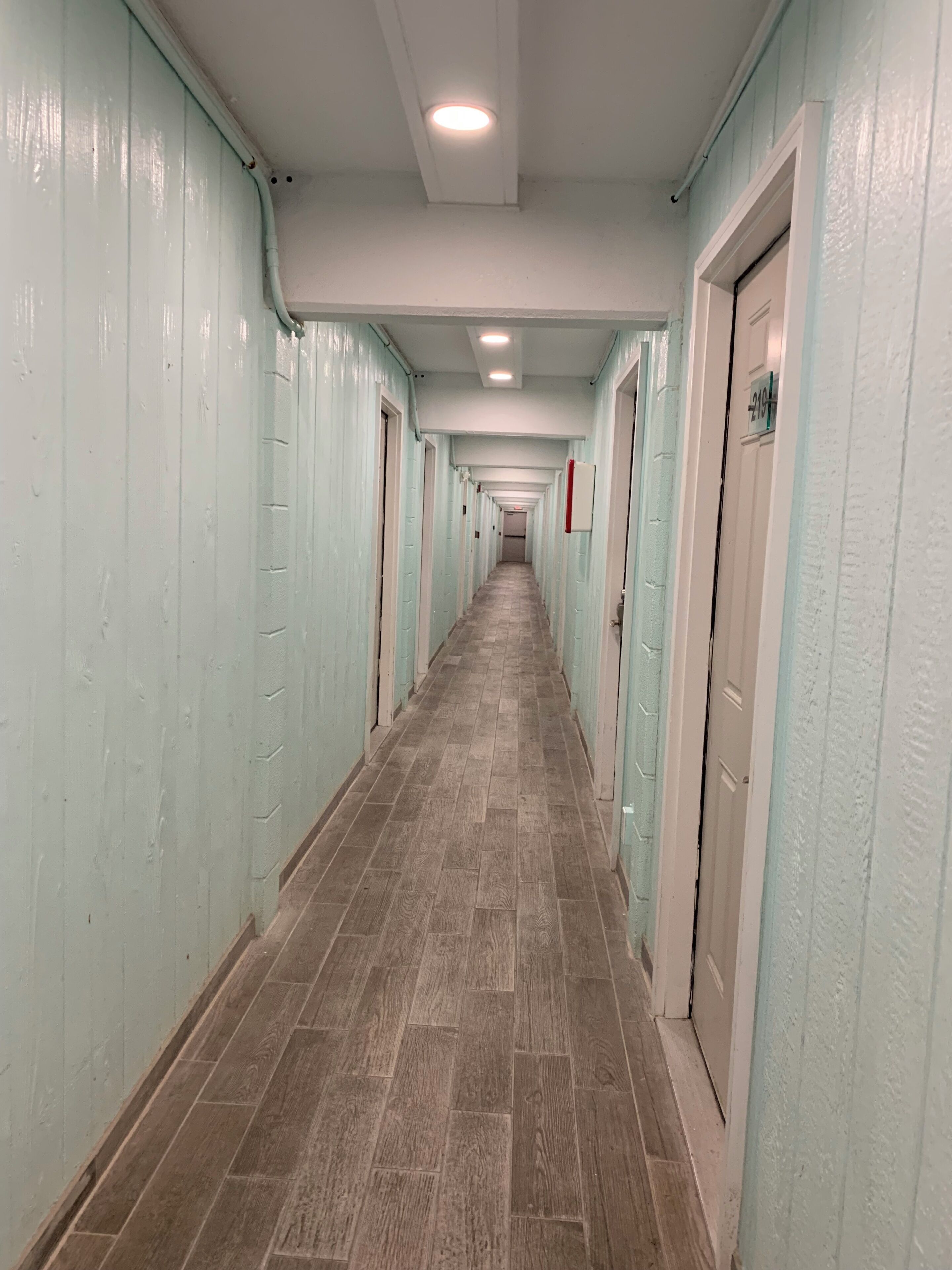 A long, narrow hallway with doors on both sides, leading to individual rooms.