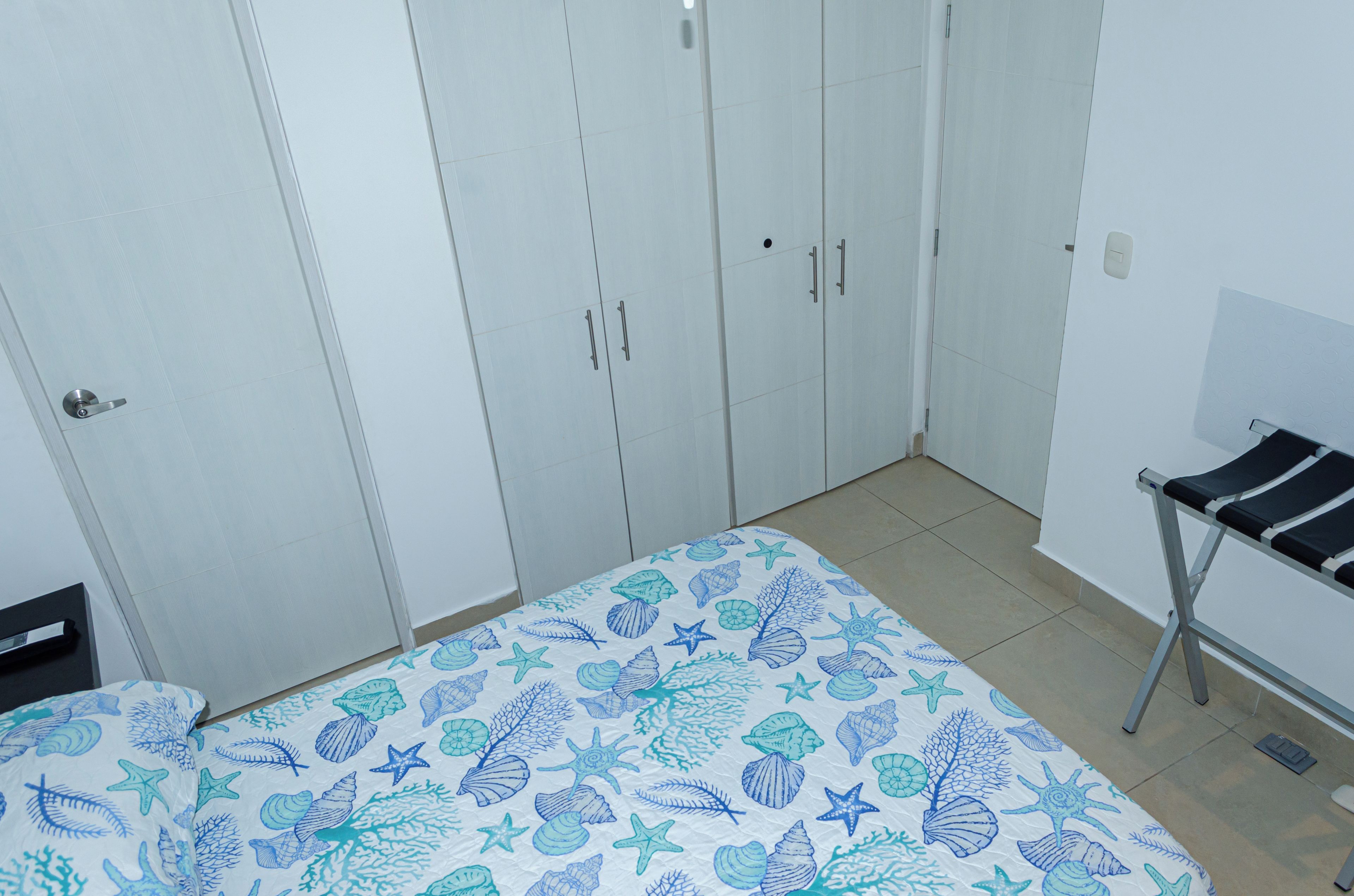 Een slaapkamer met een bed, een kast en een kleine tafel.