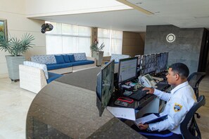 A reception area with a curved desk, two sofas with blue cushions, and potted plants. - Infinity Blue (Gaira)