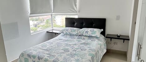 A bedroom with a bed, a ceiling fan, a window with blinds, an air conditioning unit, and a nightstand.