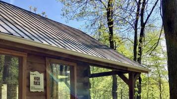 A hot tub with a wooden deck and a cabin with a sign that reads 'Welcome to High Rock.'