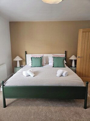 A neatly made bed with pillows and towels, a wooden wardrobe, and two bedside lamps. - Salt & Sage - Whitby (Whitby)