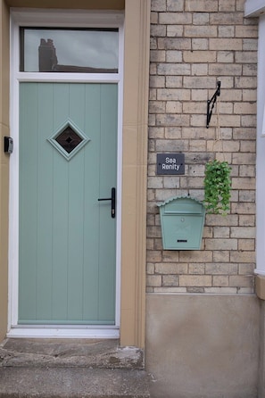 A teal door with a diamond-shaped window, a mailbox, and a sign reading 'Sea Renity' on a brick wall. - Sea Renity  - Whitby (Whitby)