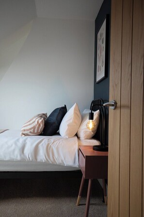 A bedroom with a bed, pillows, a bedside table with a lamp, and a door. - Sea Renity  - Whitby (Whitby)