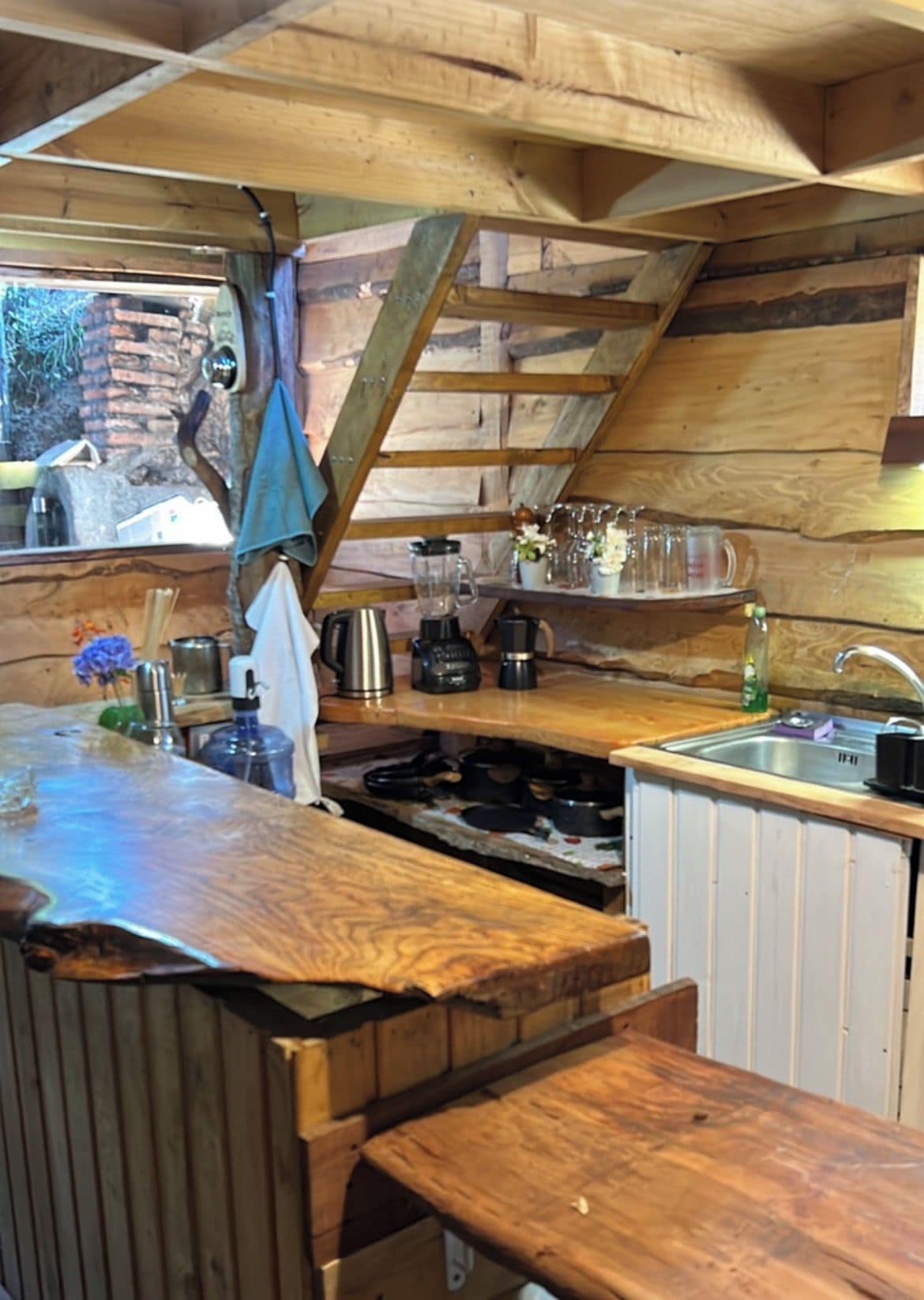 A rustic kitchen with wooden beams, a sink, and various appliances.