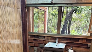 Ein kleines Badezimmer mit einem Holzbachttopf, Toilette und einer kleinen Stufe zum Duschbereich.