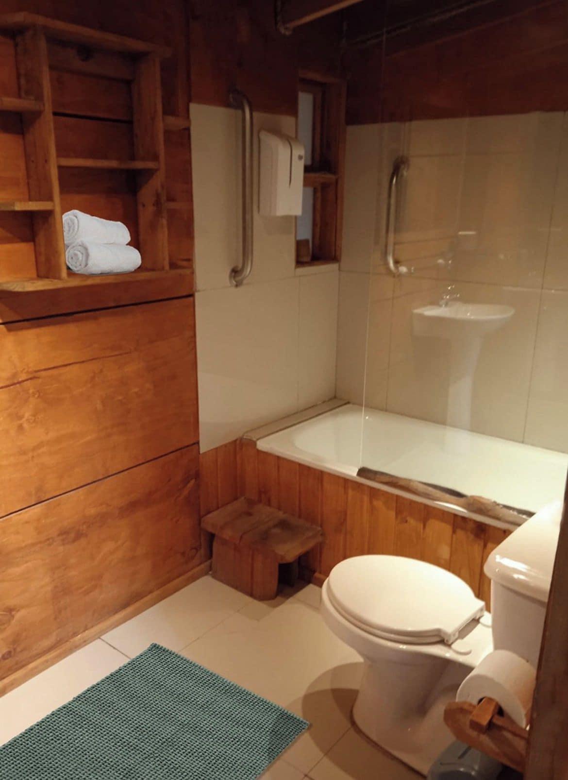 Een houten badkamer met toilet, wastafel, bad en douche.