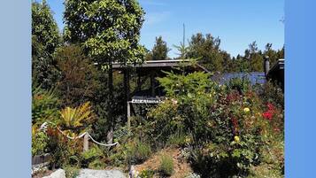 Un jardin agrémenté d’une pergola portant l’inscription « La Limon », entouré de diverses plantes et bordé d’un chemin de gravier.