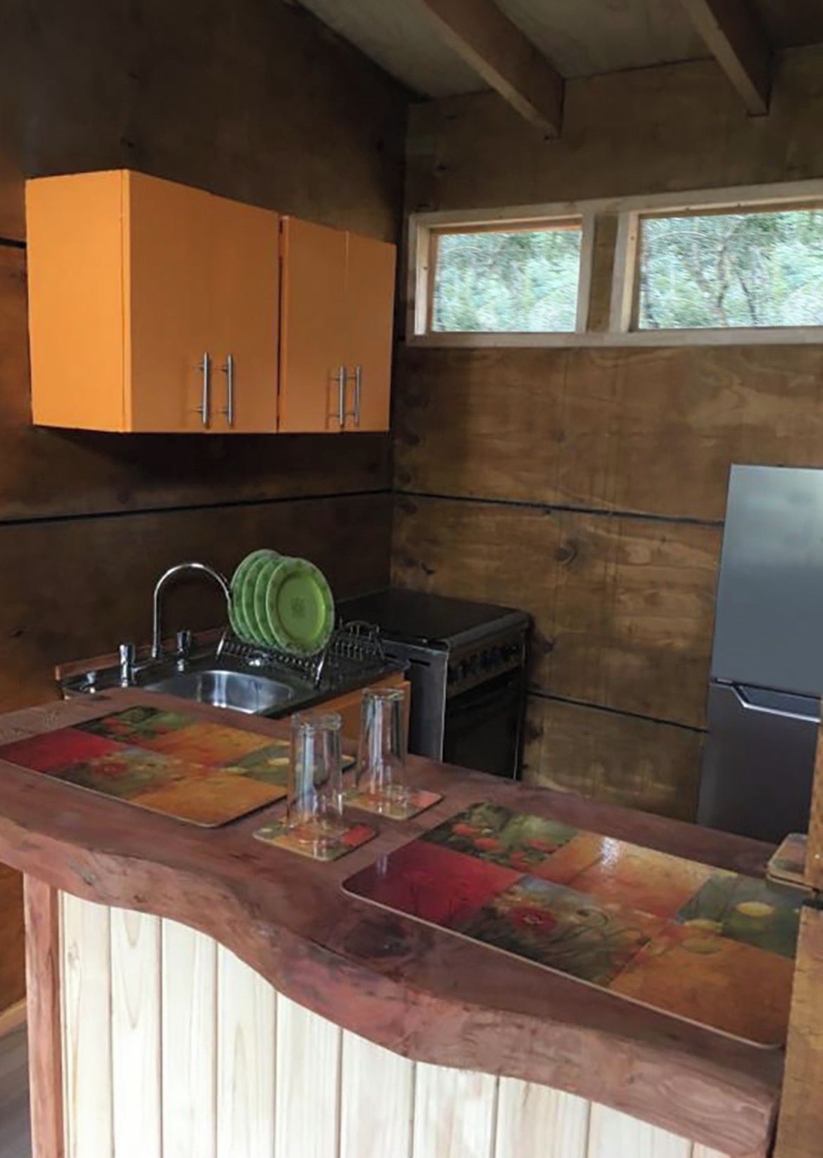 A compact kitchen with wooden cabinets, a sink, and a stove.