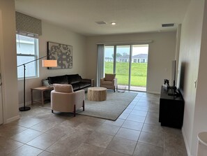 A living room with a sofa, chairs, a coffee table, a floor lamp, and a television. - Ocala Perserve Villa (Ocala)
