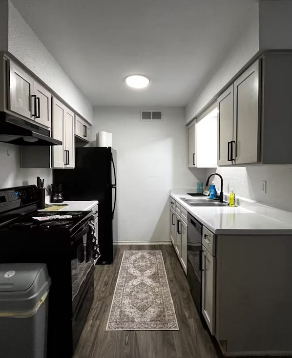 A kitchen with a stove, refrigerator, sink, and cabinets.