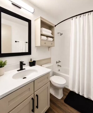 Un baño moderno con un lavamanos blanco, inodoro, bañera y cortina de ducha.