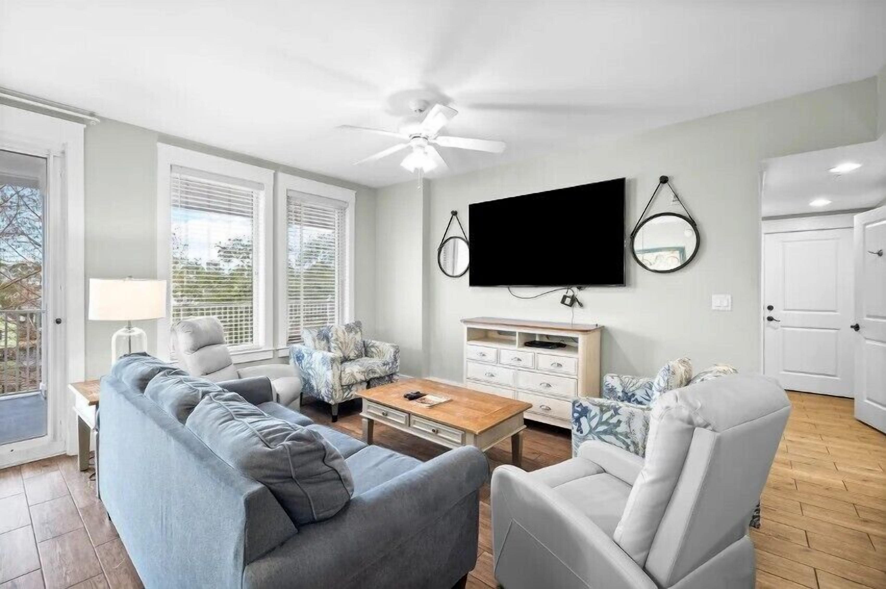 Un salon comprenant un canapé, des fauteuils, une table basse, un téléviseur et un ventilateur de plafond.