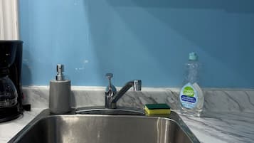 A kitchen sink with a faucet, a coffee maker, and a dish soap bottle on the counter.