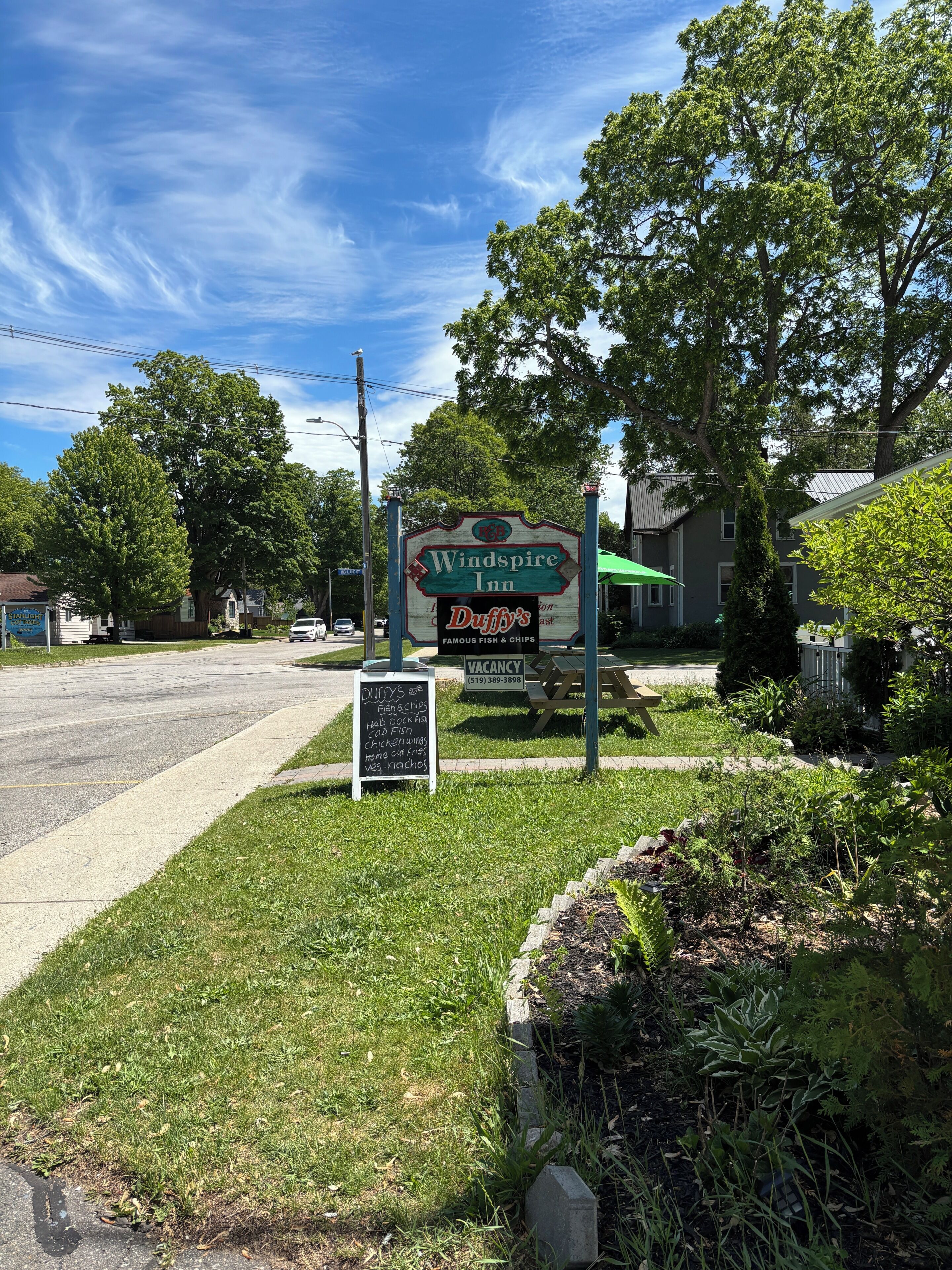 Un panneau indicateur au bord de la route pour l’auberge Windspire, avec un autre panneau à proximité indiquant l’emplacement du restaurant Duffy’s Dishes & Chips.