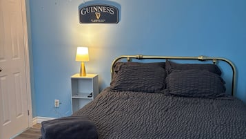 A bedroom with a bed, a nightstand with a lamp, and a wall sign.