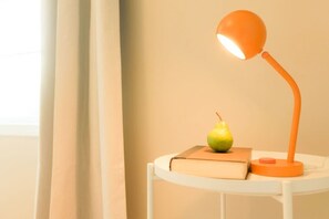 A round table with a single book and a pear, and an orange desk lamp on it. - Spacious 3BR Family Home | Bunks + Ping Pong (Peoria)