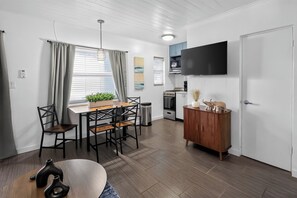 Una cocina moderna con comedor, televisor montado en la pared y un mueble de madera con objetos decorativos.
