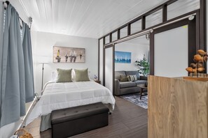Quarto moderno com uma cama grande, um sofá e uma porta de vidro deslizante para uma varanda.