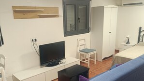 Un soggiorno con un divano blu, un armadietto bianco, una televisione e un tavolino.