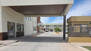 A covered walkway leading to a building with a garage door and a vehicle parked nearby.