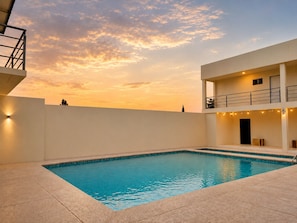 A swimming pool with a clear blue water surface, surrounded by a white tiled deck. - Magnolias Suites Hotel (Nuevo Casas Grandes)