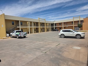 A multi-story building with a parking lot, a staircase, and a gated entrance. - Magnolias Suites Hotel (Nuevo Casas Grandes)
