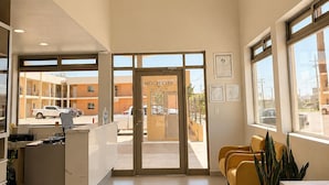 A reception area with a desk, chairs, and a door leading outside.