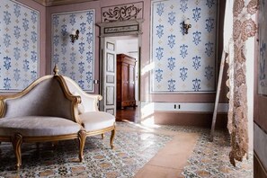 Una habitación con una silla clásica, papel tapiz estampado y un armario de madera.